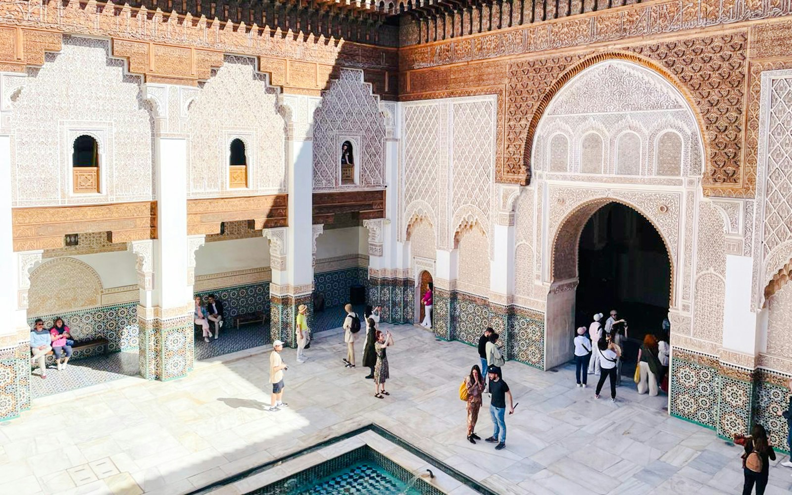 People exploring courtyard of Ben Youssef Madrasa in Marrakech, Morocco.