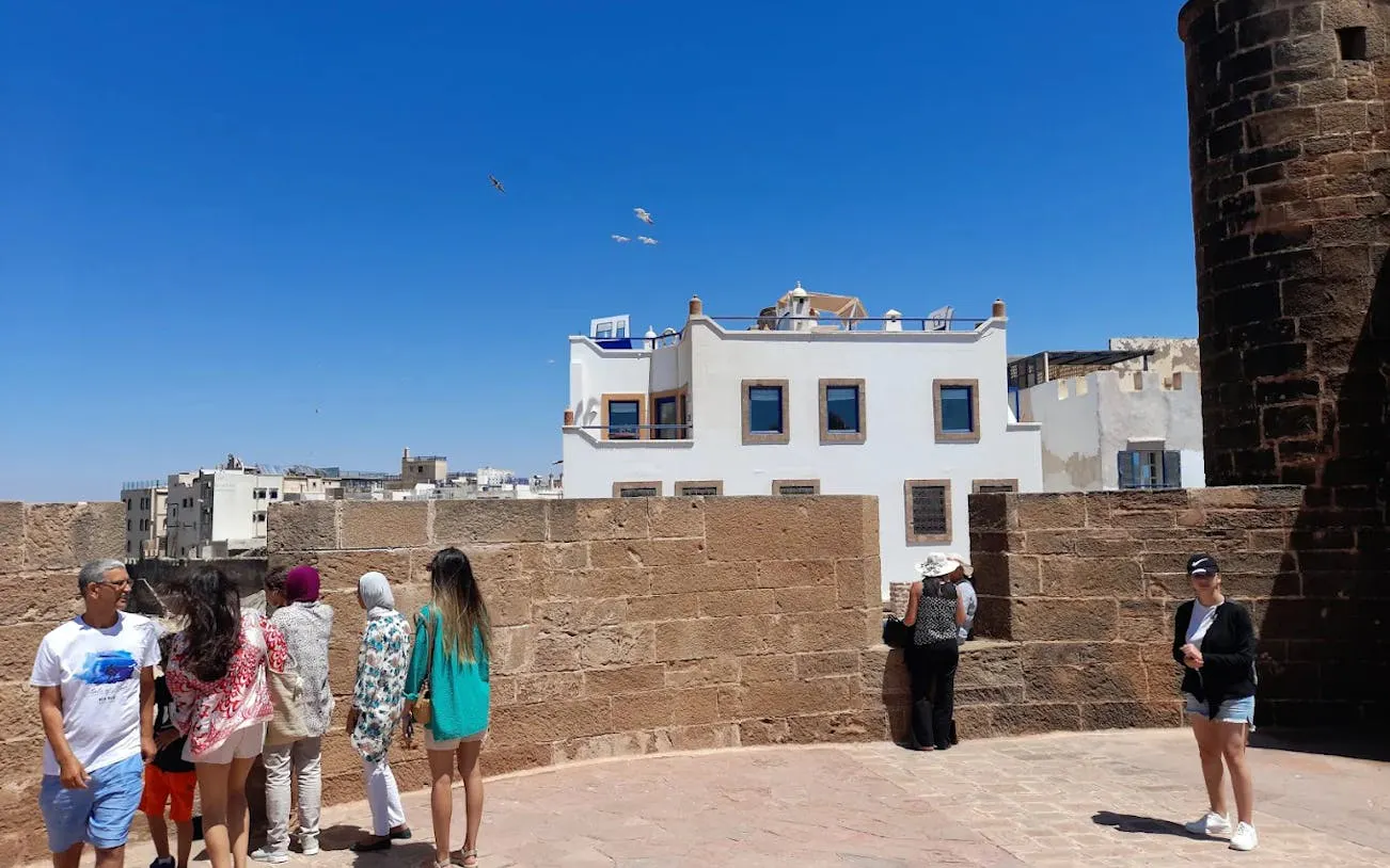 Tourists exploring the historic walls of Sqala du Port in Essaouira, Morocco.