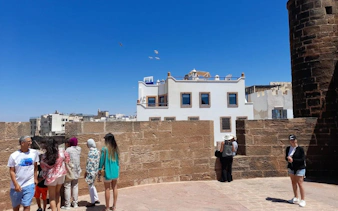 Tourists exploring the historic walls of Sqala du Port in Essaouira, Morocco.