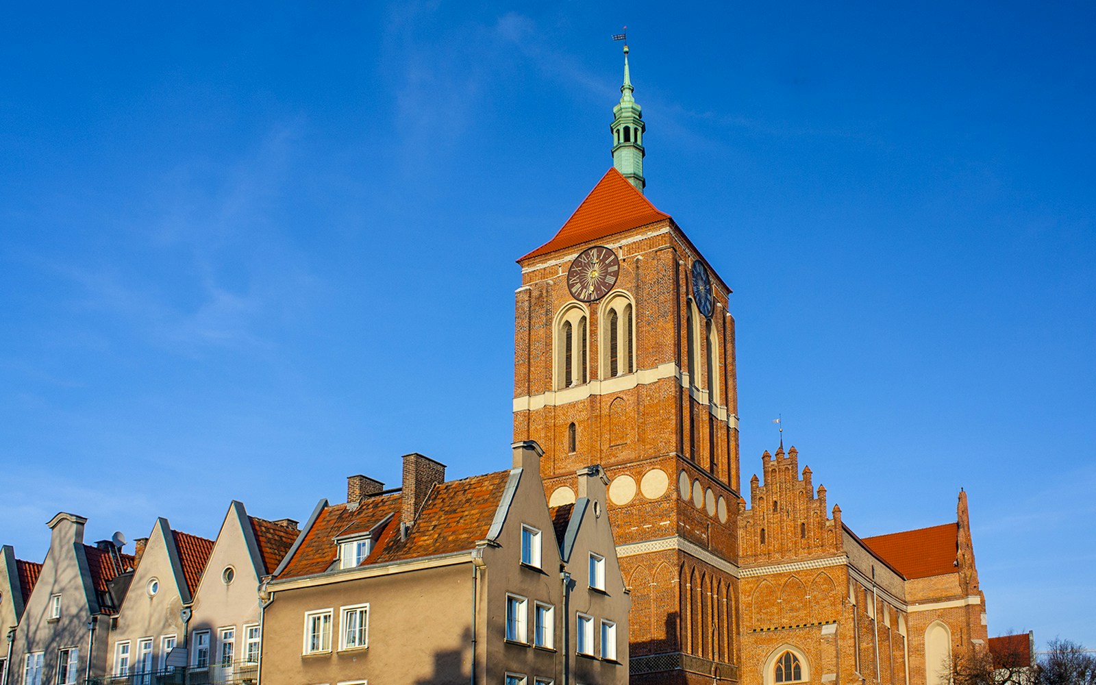 Church of St. John with clock tower in Gdansk, Poland, against blue sky.