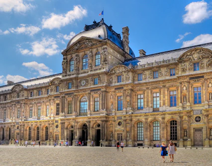 Louvre Museum courtyard with visitors walking on cobblestone.