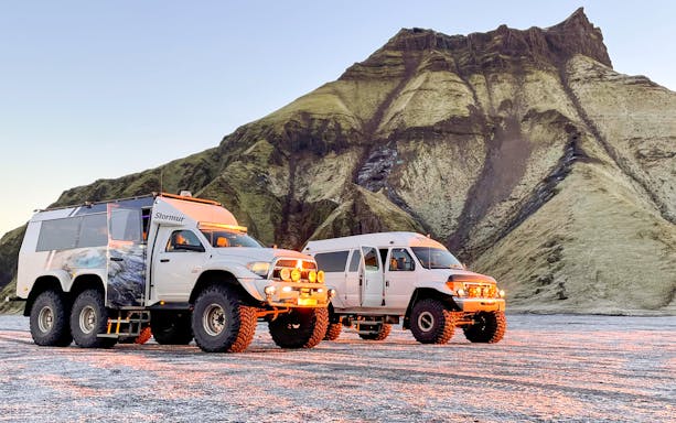 Super jeeps parked in front of a rugged mountain landscape during Troll Expeditions tour.