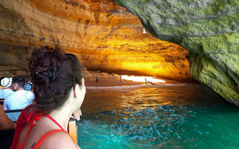 Guided boat tour inside Benagil Caves with people viewing the illuminated cave interior.