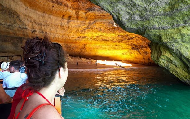 Guided boat tour inside Benagil Caves with people viewing the illuminated cave interior.