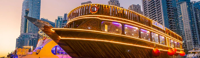 Alexandra Dhow Cruise illuminated at Dubai Marina during sunset.