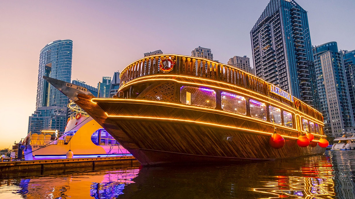 Alexandra Dhow Cruise illuminated at Dubai Marina during sunset.