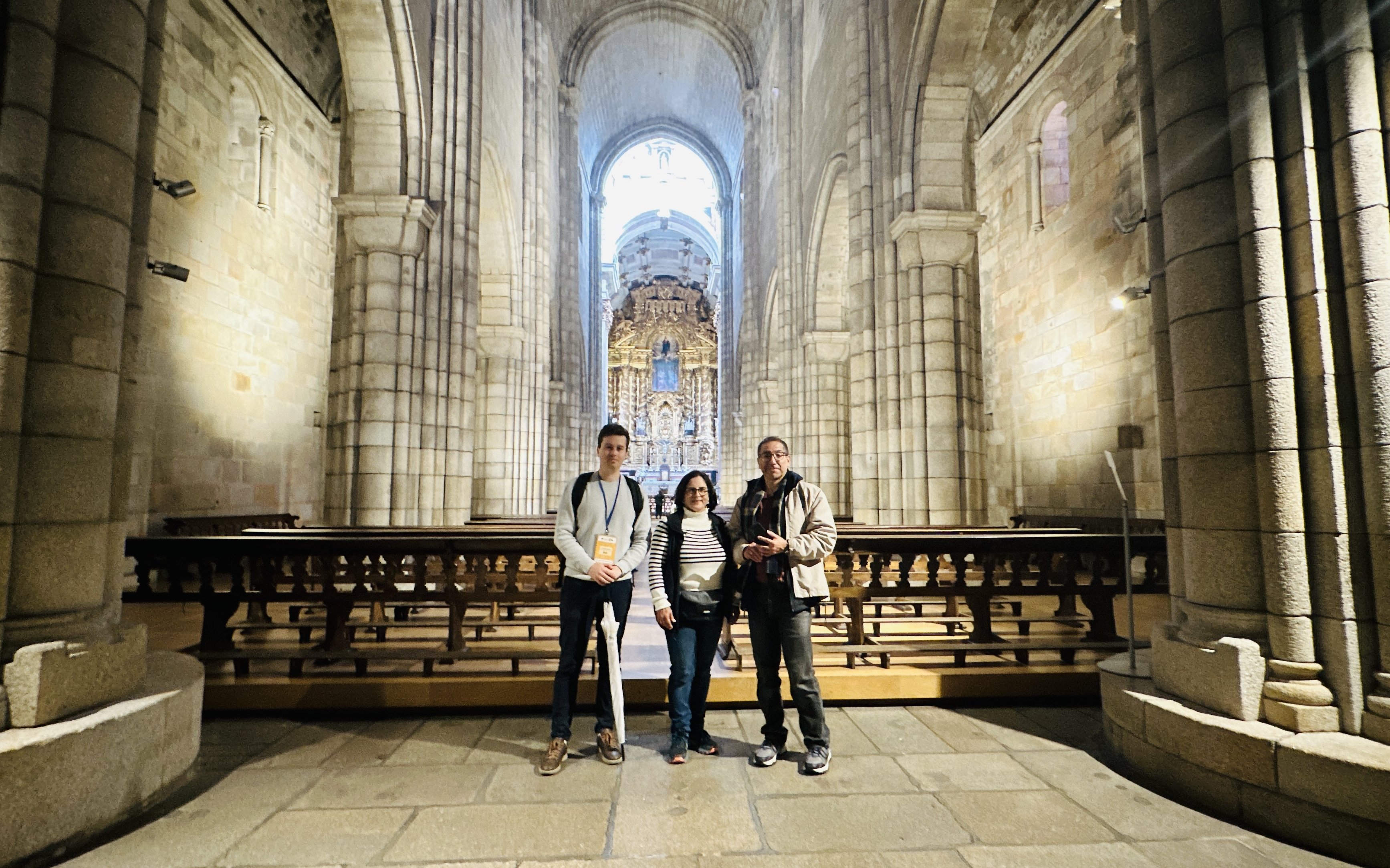 Tourists with guide inside Porto Cathedral, Portugal, near ornate altar.