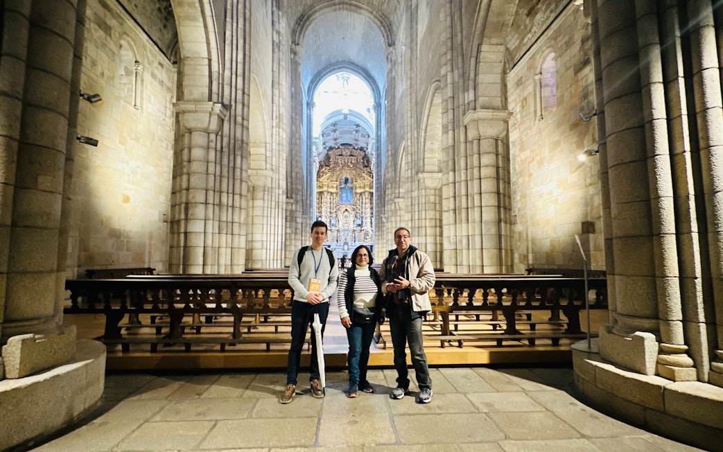 Tourists with guide inside Porto Cathedral, Portugal, near ornate altar.