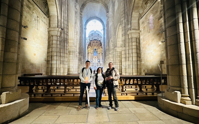 Tourists with guide inside Porto Cathedral, Portugal, near ornate altar.