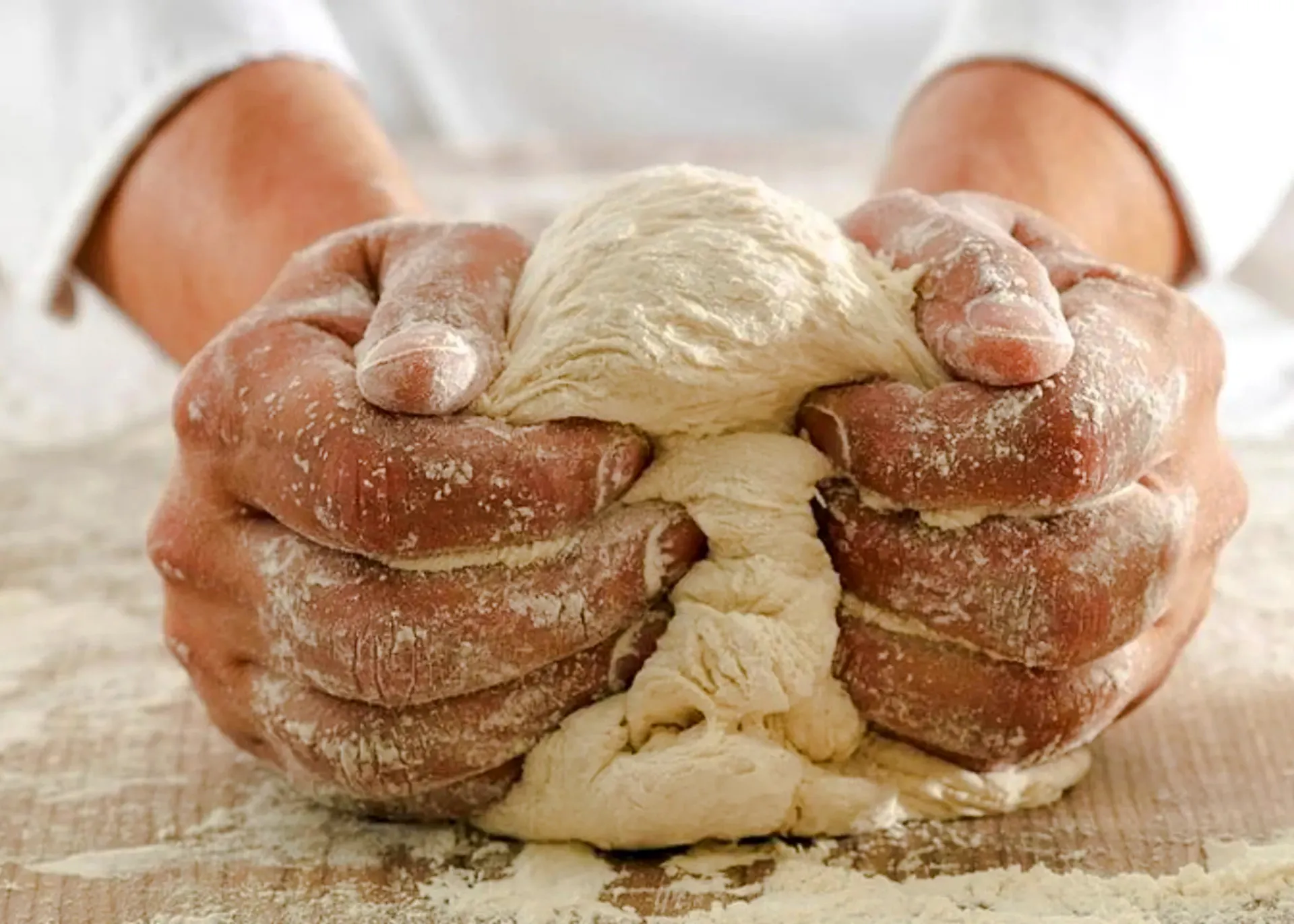 Hands kneading dough during a Genoese cooking lesson in Genoa.