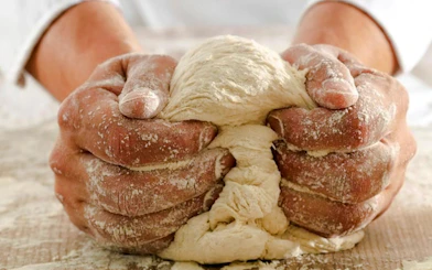 Hands kneading dough during a Genoese cooking lesson in Genoa.