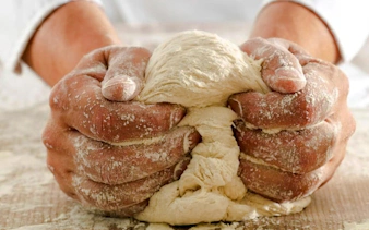 Hands kneading dough during a Genoese cooking lesson in Genoa.