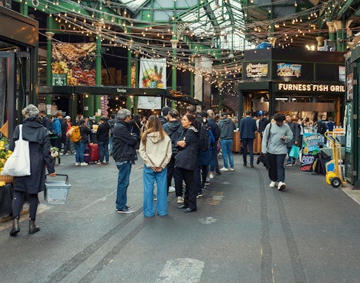 Crowd exploring food stalls at Borough Market, London.