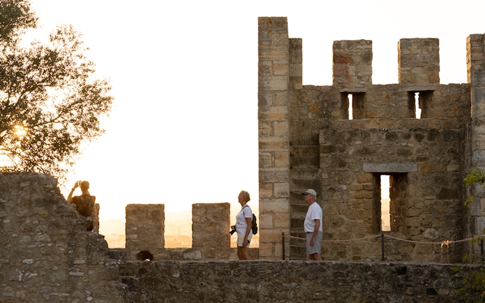 Visitors exploring St George's Castle with a guide at sunset.