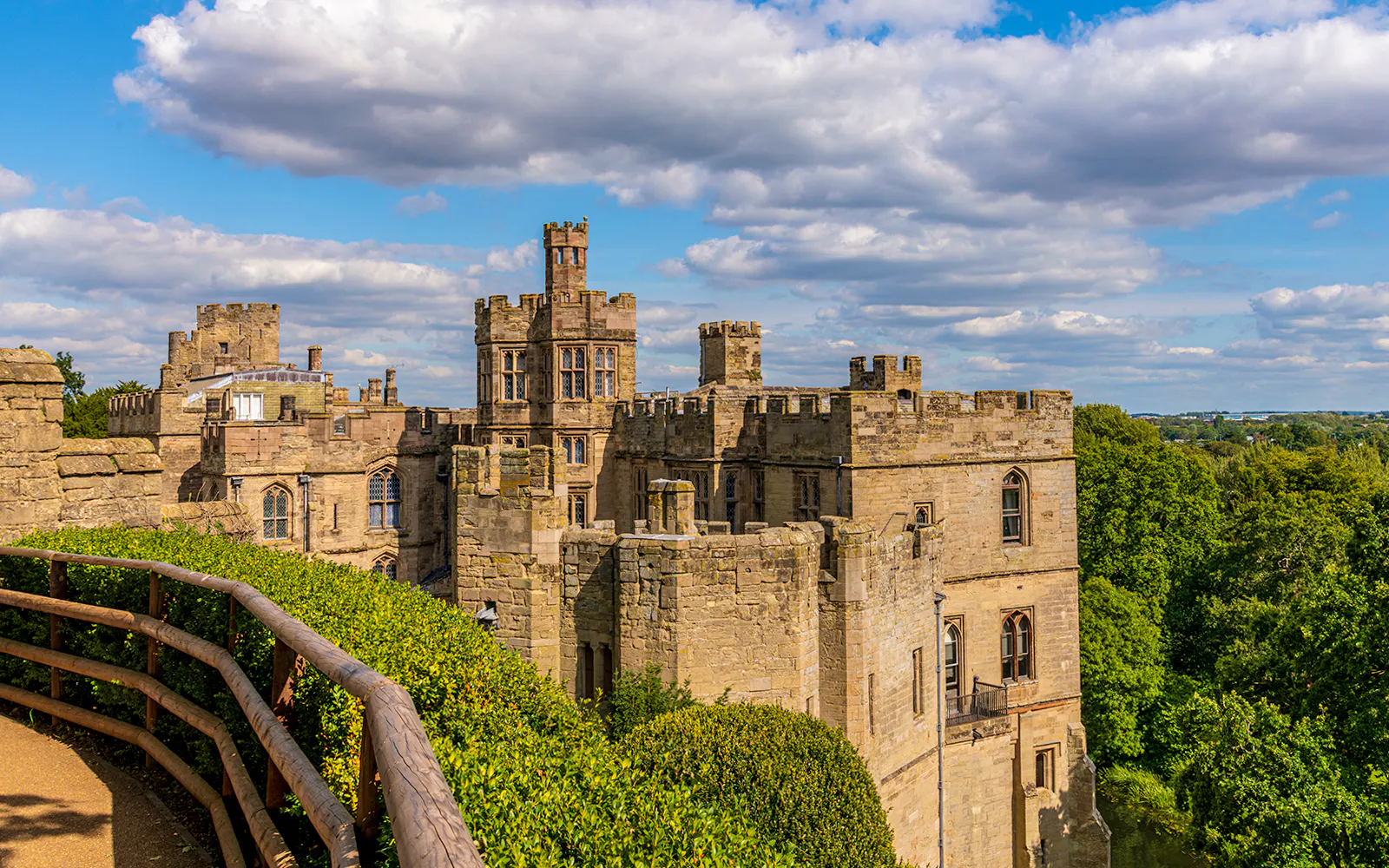Warwick Castle towers overlooking lush greenery and distant landscape.