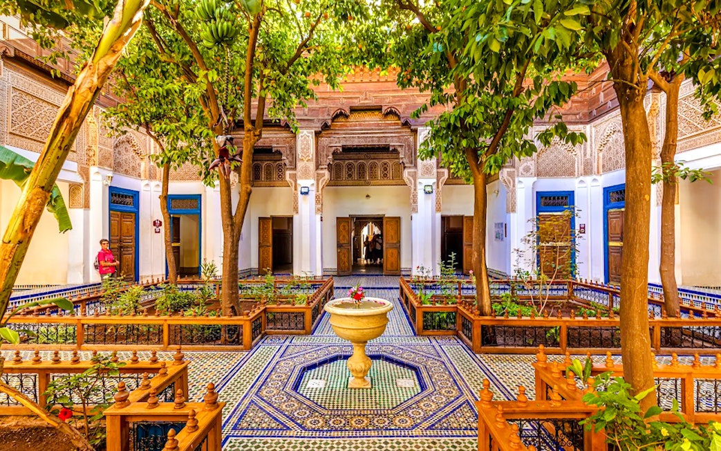 Bahia Palace courtyard with intricate tilework and lush greenery in Marrakech, Morocco.
