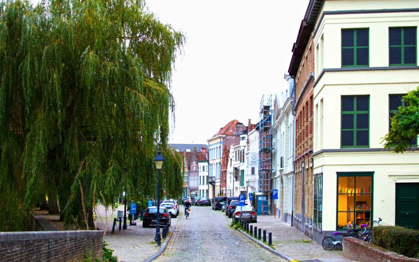 Cobbled street in Patershol, Belgium, lined with historic houses and trees.