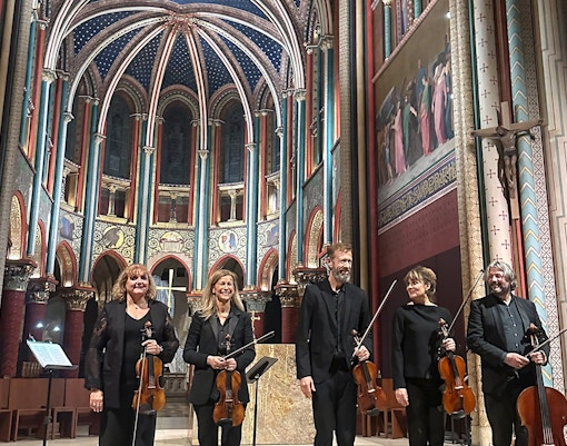 Visitors enjoying a mesmerizing concert at Sainte Chapelle, a historic gothic chapel in Paris, France