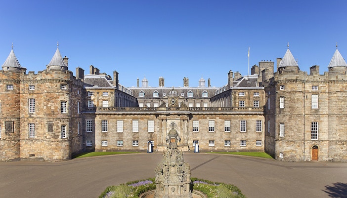 Tourists exploring the historic Palace of Holyroodhouse entrance with tickets in hand, Edinburgh