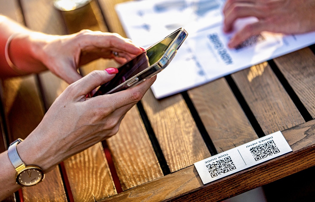 Guests using audio guide on Budapest Danube River nighttime sightseeing cruise with city lights in background