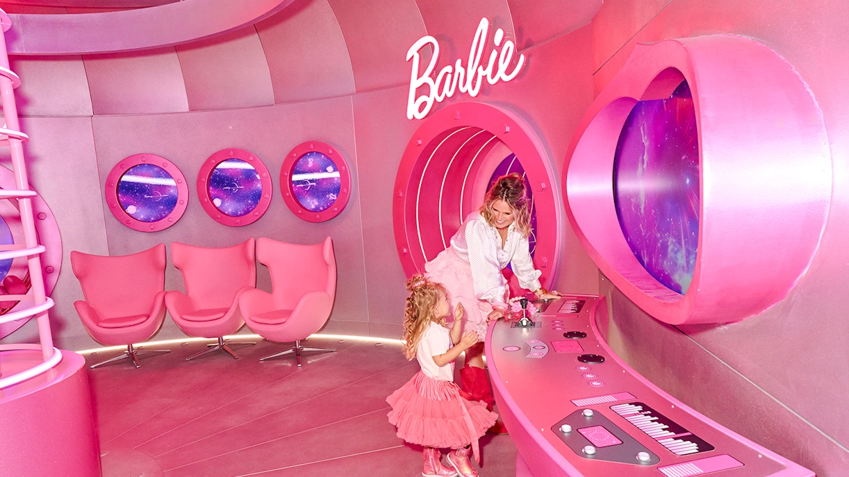 Guests exploring the pink Barbie rocketship interior with control panels and space-themed windows.