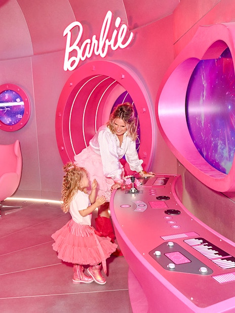 Guests exploring the pink Barbie rocketship interior with control panels and space-themed windows.