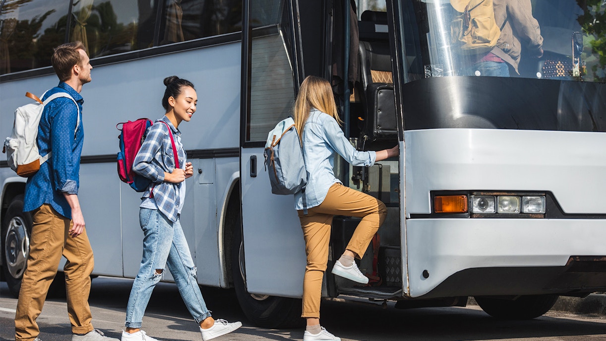 Shared bus transfer service in a scenic coastal area with passengers boarding.