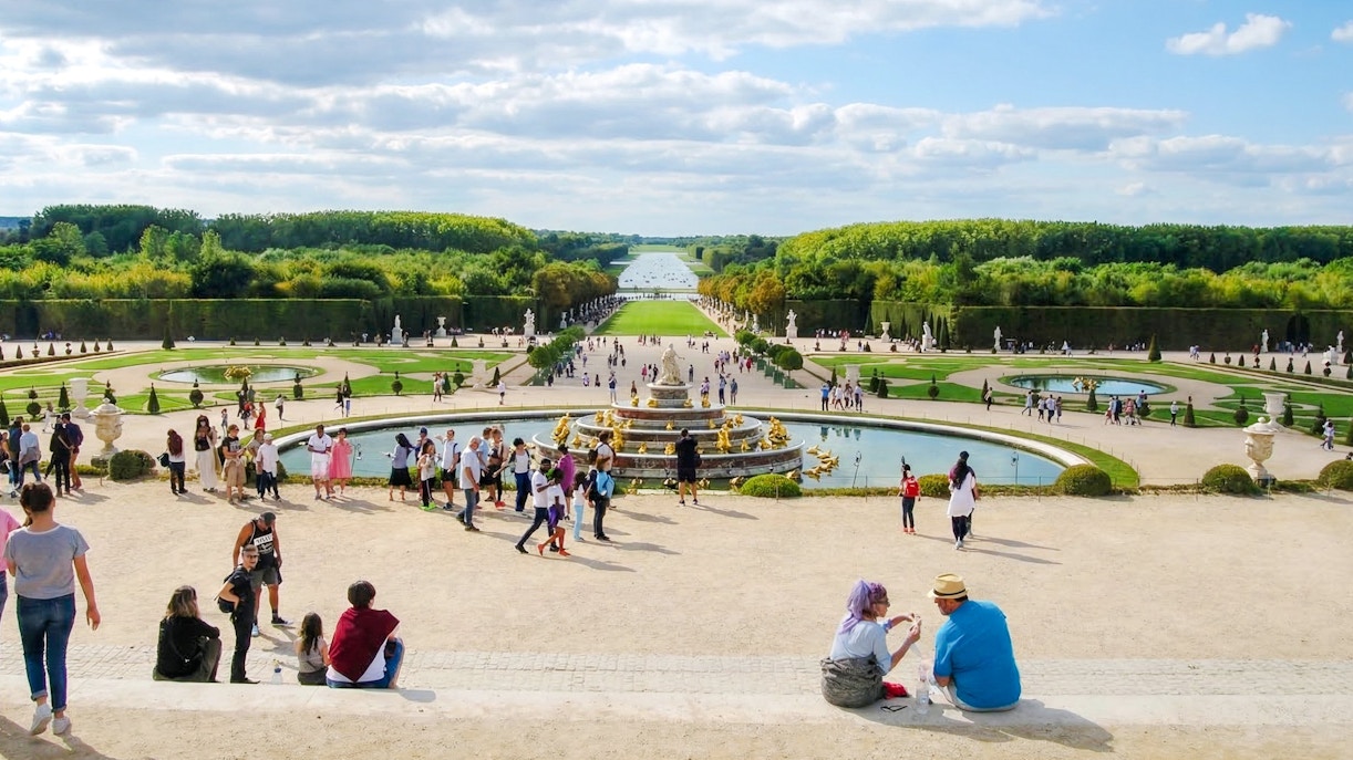 Visitors exploring the gardens and fountains at the Palace of Versailles, France.