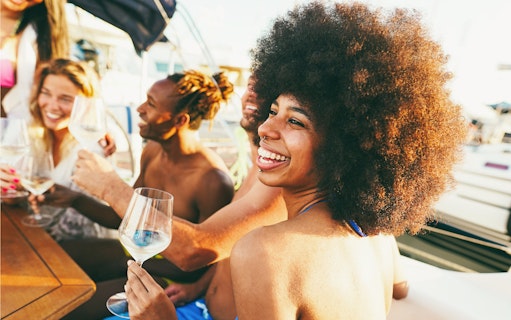 Friends enjoying wine on a boat party outdoors.