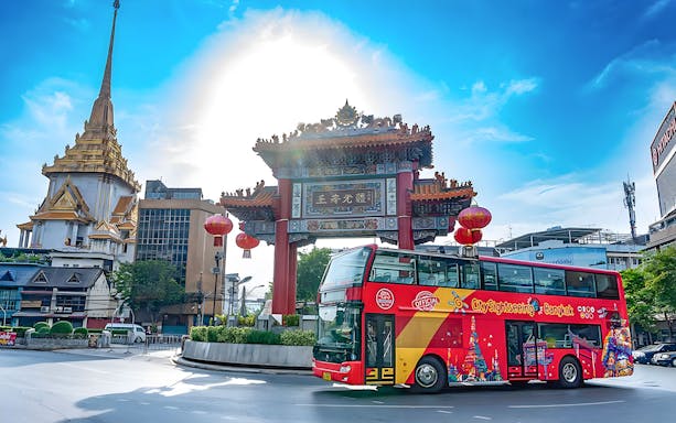 Bangkok hop-on hop-off bus near Chinatown gate with temple in background.