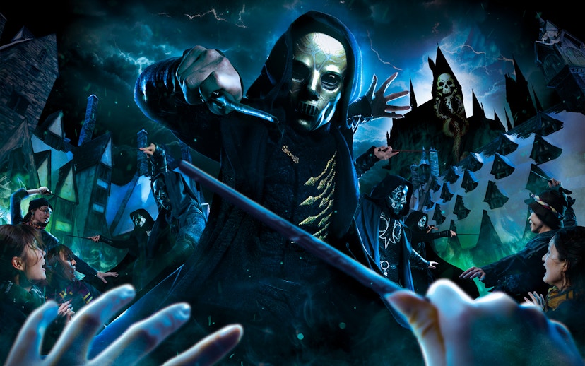 Masked figures with wands in a magical battle scene at a theme park attraction.