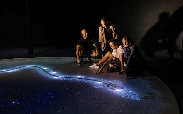 Group exploring star map at Dark Sky Indoor Cultural Astronomy Experience.