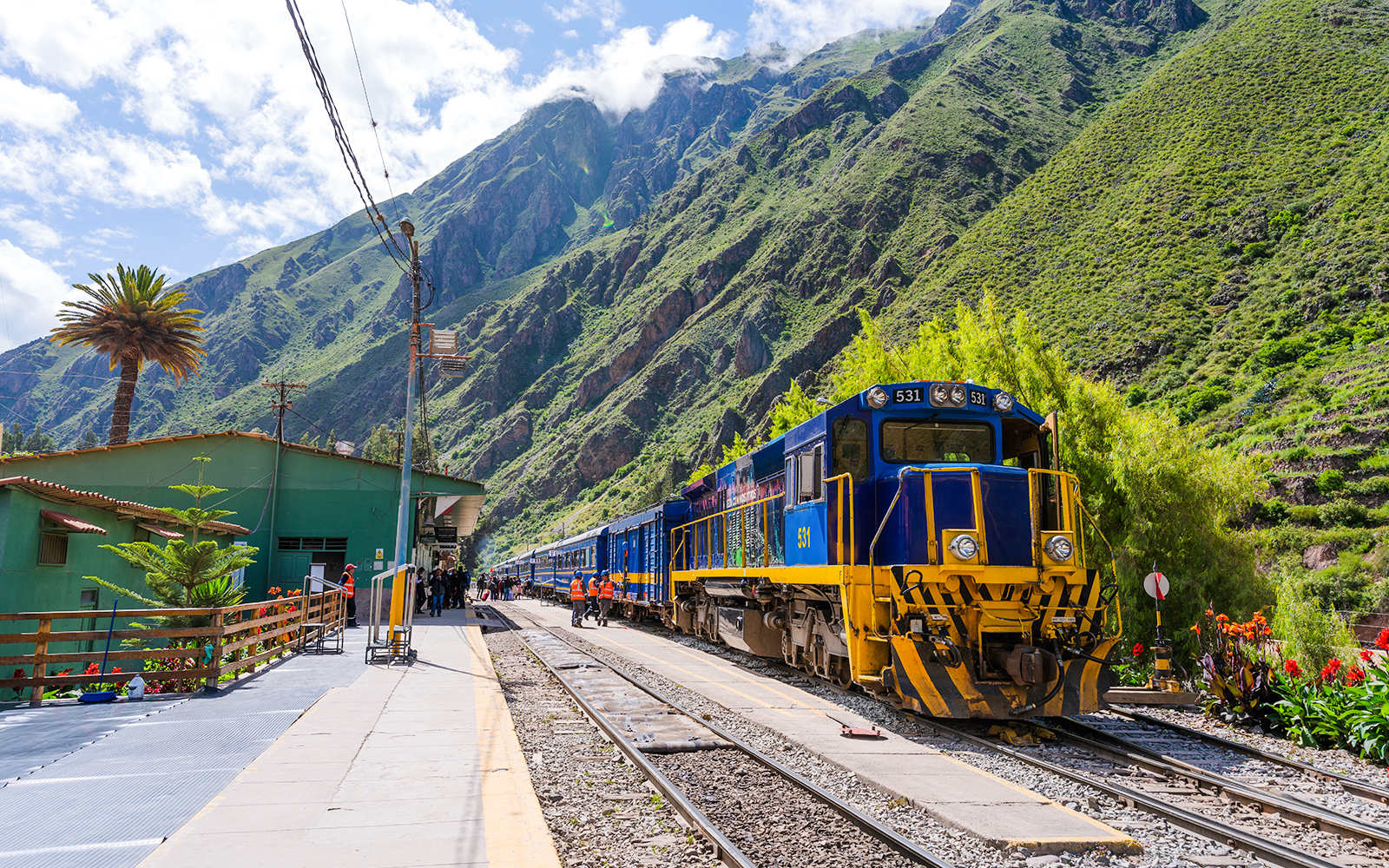 PeruRail train at station with Andes mountains in background, en route to Machu Picchu.