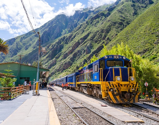 PeruRail train at station with Andes mountains in background, en route to Machu Picchu.
