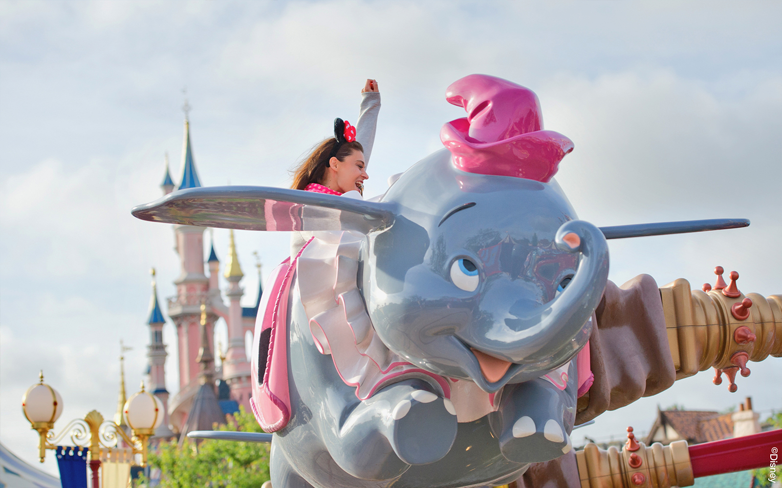 Rider on Dumbo ride at Disneyland Paris with castle in background.