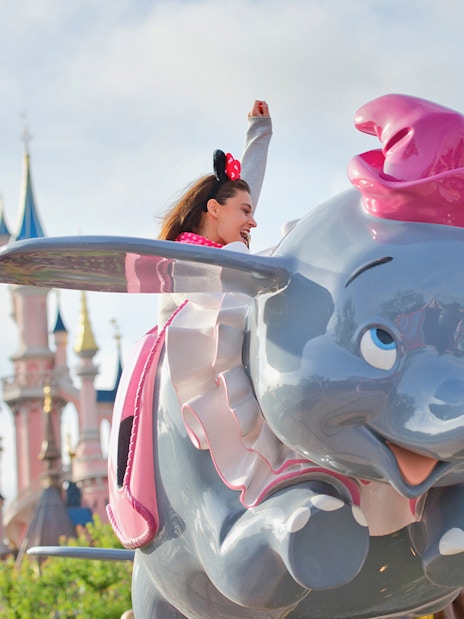 Rider on Dumbo ride at Disneyland Paris with castle in background.