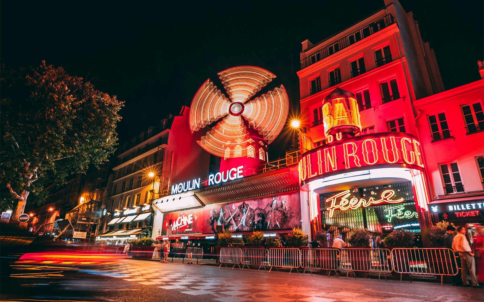 Moulin Rouge exterior with iconic red windmill in Paris, France.