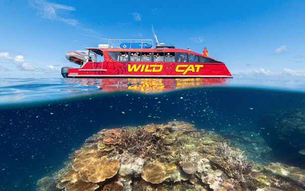 Red boat on Outer Reef Snorkel Adventure above vibrant coral reef.