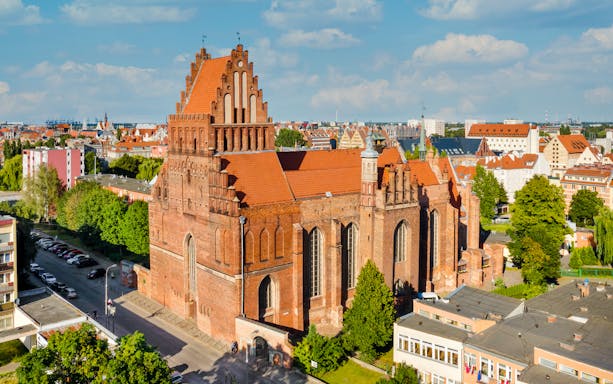 Gdańsk Gothic church with red brick facade and cityscape in the background.