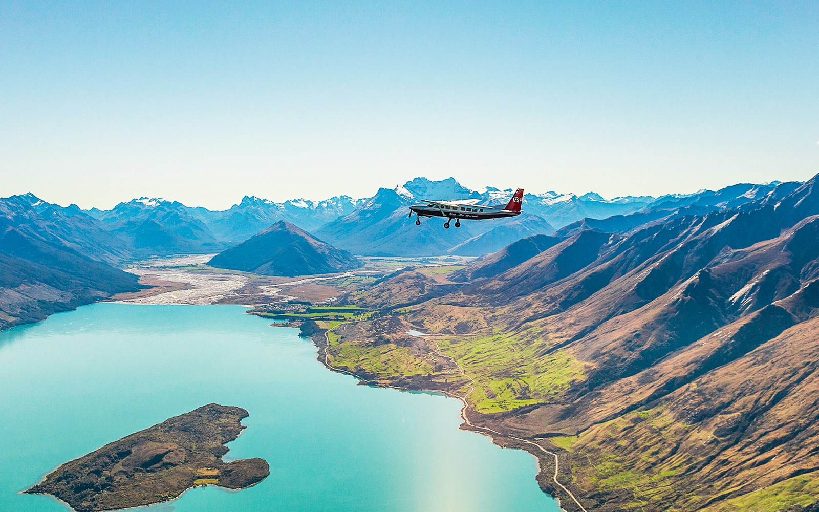 Plane flying over a lake with mountains during a scenic flight to Milford Sound.