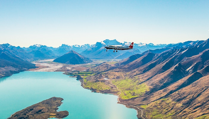 Scenic flight over lake towards Milford Sound, New Zealand, with mountains in view.