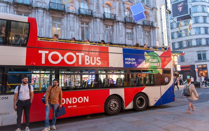 Open-top tour bus in London at night with people sightseeing.
