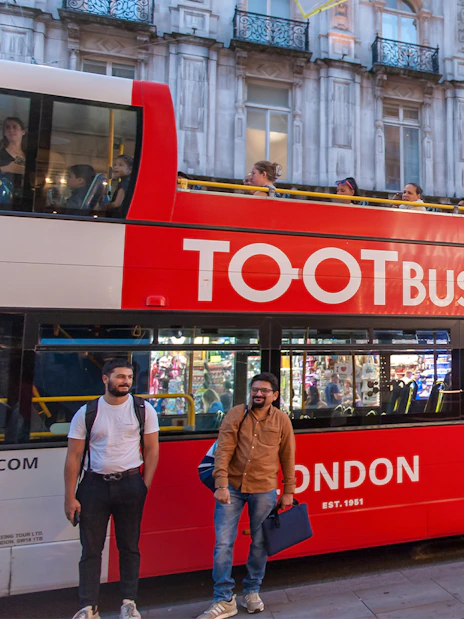 Open-top tour bus in London at night with people sightseeing.