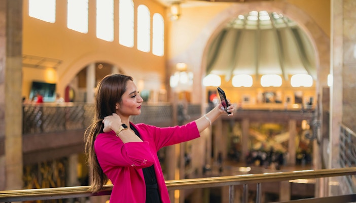 Women taking selfie inside Palacio de Bellas Artes, Mexico, showcasing its ornate interior design.