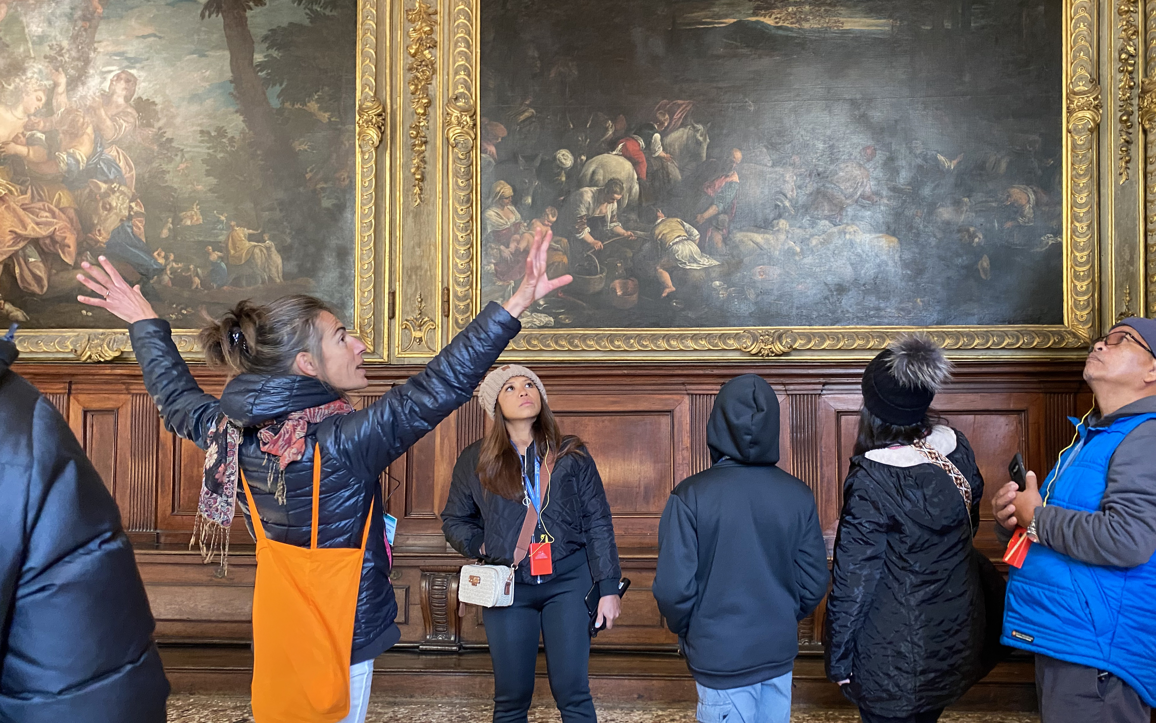 Visitors with tour guide inside Doge's Palace viewing artwork.