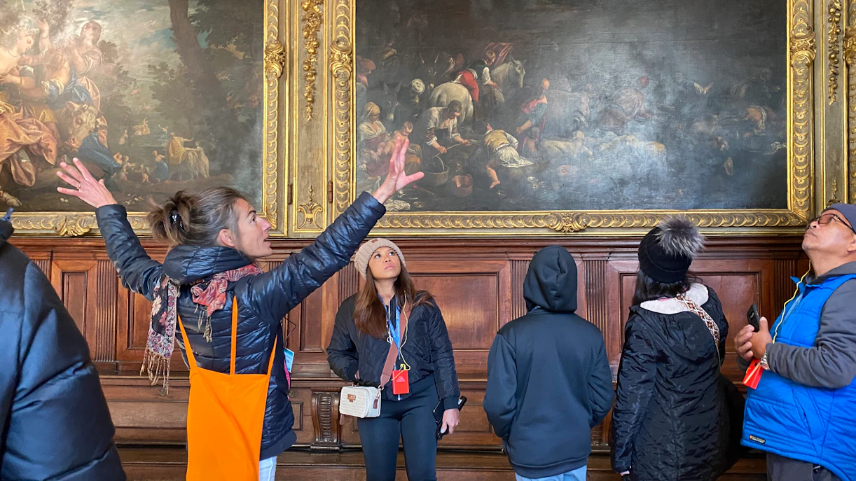 Visitors with tour guide inside Doge's Palace viewing artwork.