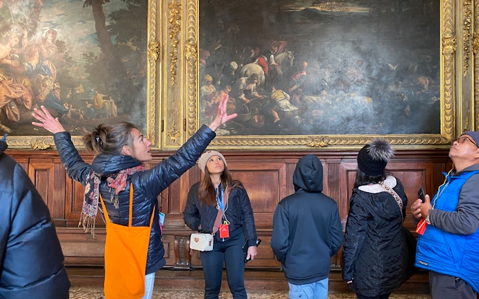 Visitors with tour guide inside Doge's Palace viewing artwork.