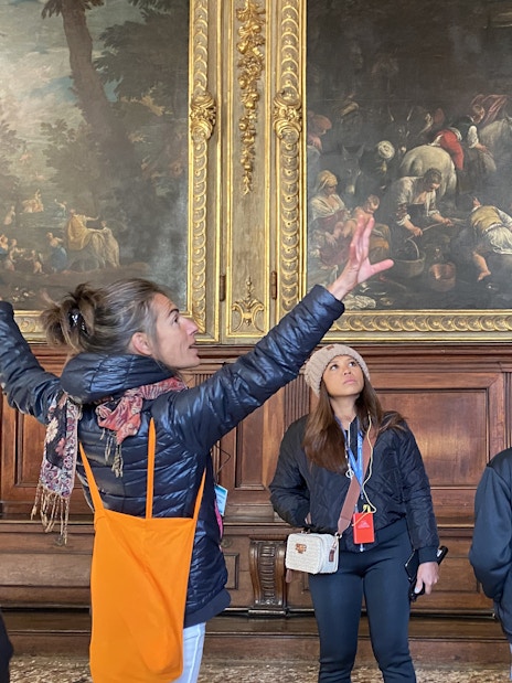 Visitors with tour guide inside Doge's Palace viewing artwork.
