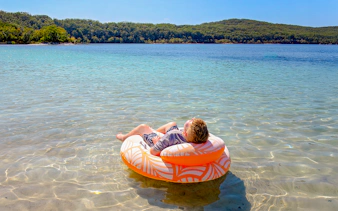 Boy floating on an inflatable ring in Lake McKenzie, Fraser Island, K'gari.