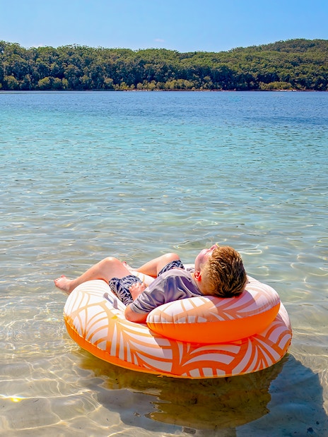 Boy floating on an inflatable ring in Lake McKenzie, Fraser Island, K'gari.
